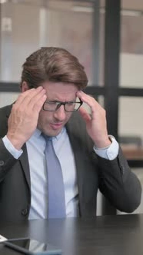 Businessman having Headache while Sitting in Office, vertical