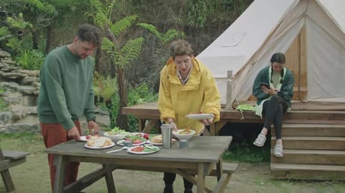 Friends Camping and Sharing a Meal Outdoors