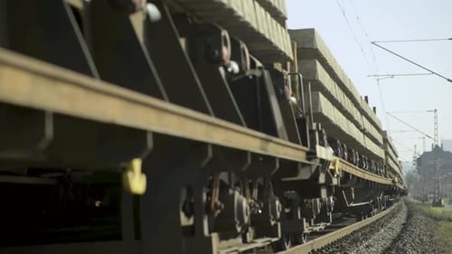 Trem ferroviário de carga carregado com materiais industriais se movendo ao longo dos trilhos, dia ensolarado