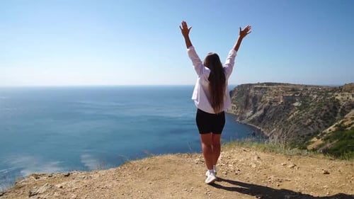 Woman Summer Travel Sea Happy Carefree Lady in a Pink Shirt and White Skirt Raises Arms on Sea Ocean