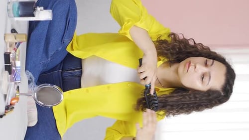 Vertical video of Young woman combing her hair. Hair care.
