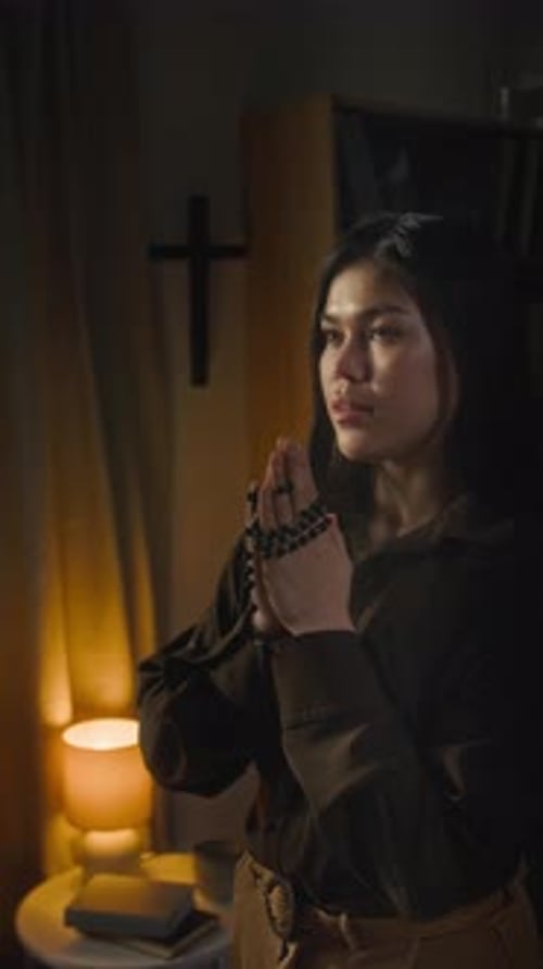 Young Woman Praying Quietly at Night with Rosary