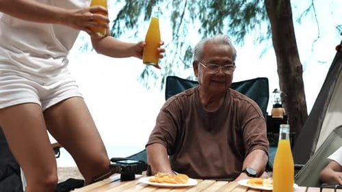 Group of people family camping on the beach drinking juice refreshment together enjoy