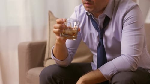 Depressed man drinks whiskey indoors looking sad