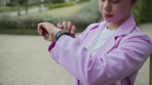 Intercultural Woman Checking Smartwatch when Walking in City Park