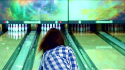 Brunette Girl Joyfully Knocks Down Bowling Pins