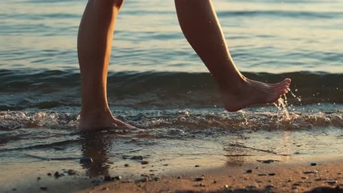 Woman Walking Barefoot on the Beach at Sunset