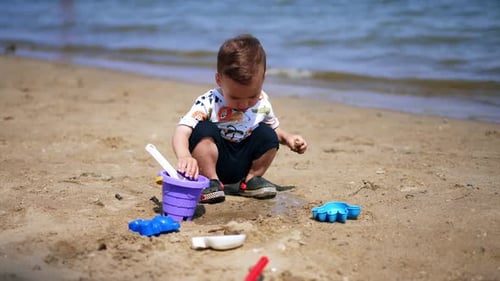 Happy Child Plays with Toys on Beach