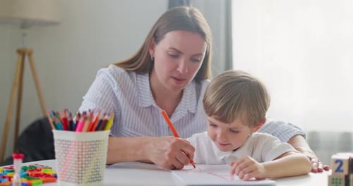 Woman and Child Drawing Together at Table