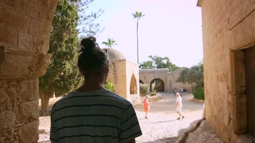 Modern Man Walking Among Dark Ancient Buildings In Slow Motion. Back View Of Man Walking In Easte...