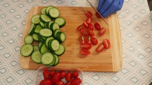 Gloved Person Cutting Tomatoes on Wood Board