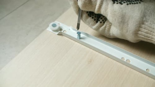 Carpenter Installing Drawer Slide on Wooden Panel Using Screwdriver