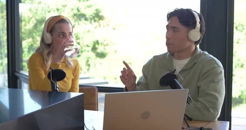 Les co-animateurs se penchent, expliquent, écoutent à la table d'enregistrement avec des micros tout en collaborant