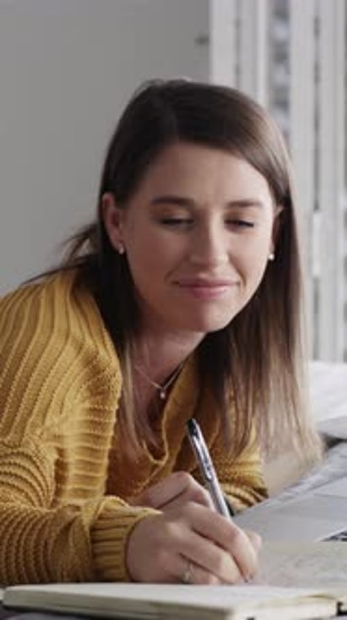 Smiling Woman Writing in Notebook at Home