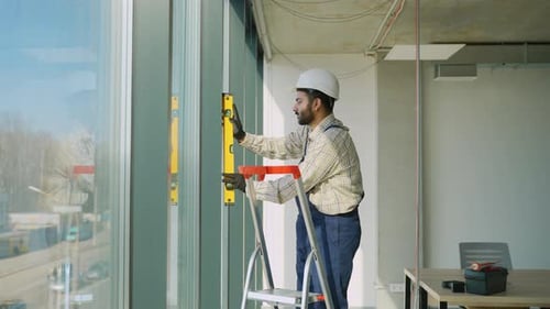 Construction Worker Using Spirit Level on a Window