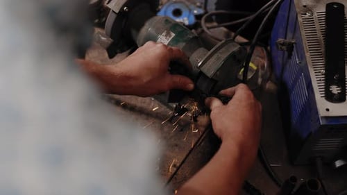 Cinematic footage of mechanic breaking a chain open with a whetstone top down