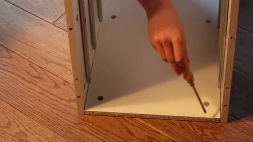 Close Up Of Boy Hand Assembling Shelf Parts On The Floor,