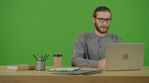 Man at Desk Talking to Laptop Green Screen