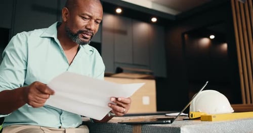 Architect, laptop or black man with paperwork for building plan, safety or maintenance in home
