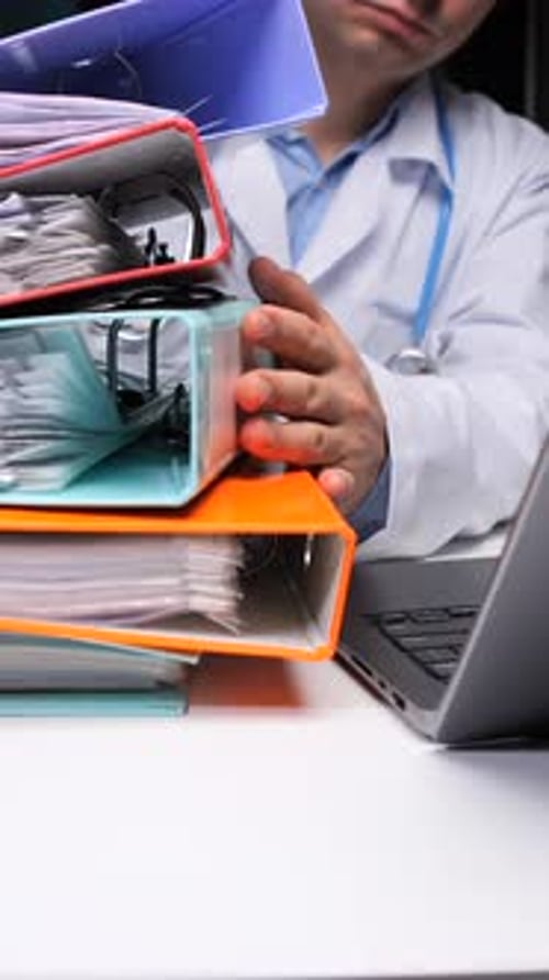 Doctor with Stack of Files and Laptop Computer