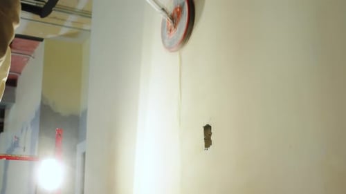 Construction Worker is Sanding a Drywall Surface Using a Longhandle Electric Drywall Sander Worker