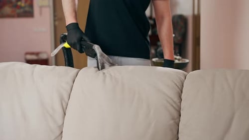 Man Cleaning Couch With Wet Vacuum