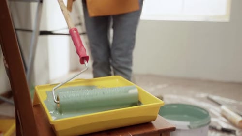 Painter Dipping Paint Roller Into Tray with Green Paint for Painting Walls