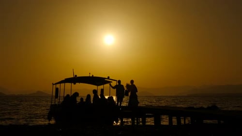 Silhouetted People on Boat and Pier at Sunset