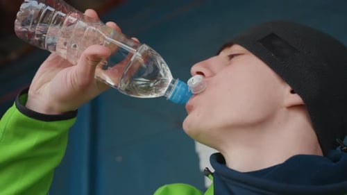 Man Drinking Water Outdoors Man in Hoodie Taking Quick Water Break Outdoors Athletic Man in Casual