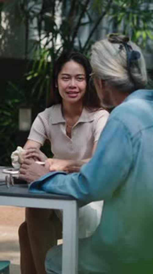 Young Asian Woman Sitting with Her Old Whitehaired Father Outdoors Together on a Quiet Terrace