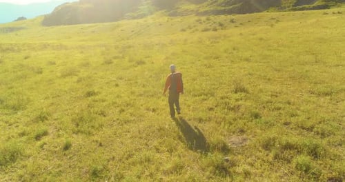 Flight Over Backpack Hiking Tourist Walking Across Green Mountain Field Huge Rural Valley at Summer