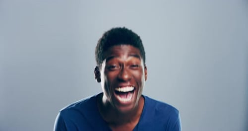 4k video footage of a young man laughing against a grey studio background