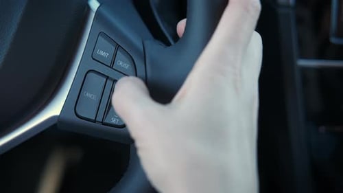 Hand Pressing Cruise Control Button on Steering Wheel