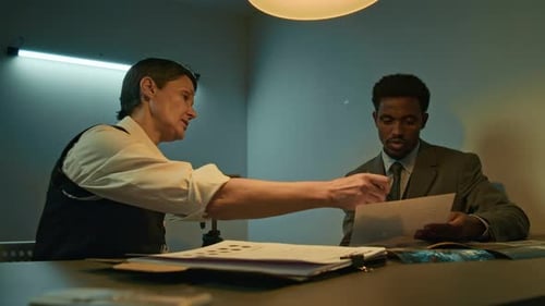 Woman Interrogates Man with Evidence in Office