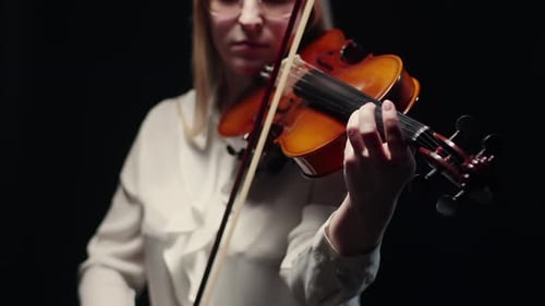 Woman Plays Violin in Dramatic Lighting