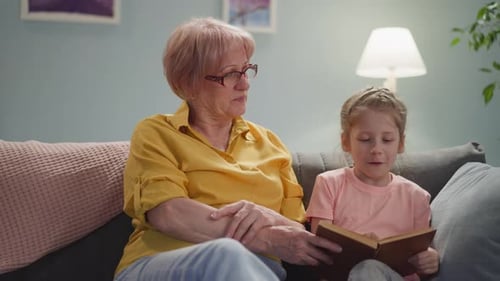 Girl Reads with Senior Woman Inside Home