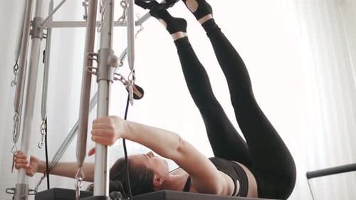 Woman Doing Inverted Pilates Exercise on Reformer Machine