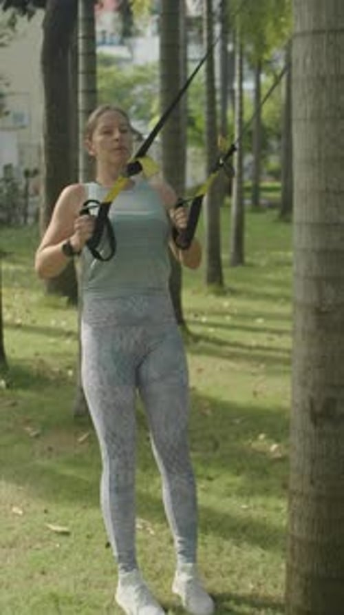 Femme faisant des rangées de sangles de suspension dans un parc