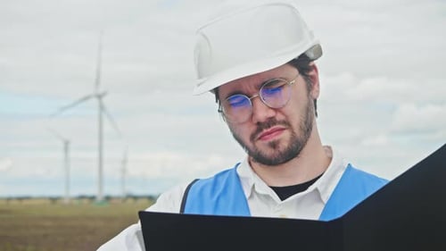 Chief Engineer Wearing Construction Helmet Glasses and Vest Studies Documentation and Drawings for