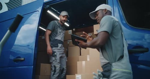 Multiethnic Workers Unloading Cardboard Boxes with ECommerce Goods From Delivery Truck