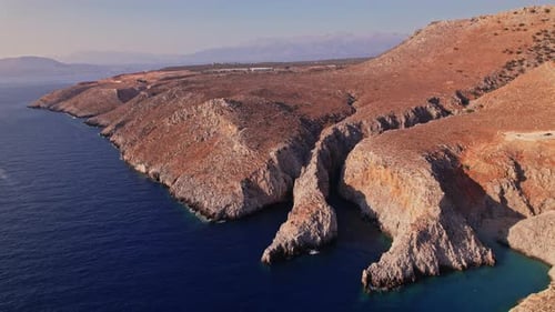 Breathtaking coastline view of rocky cliffs and deep blue sea at sunset