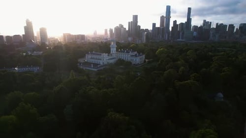 Drone circling the backlit Government house in the Kings Domain park of Melbourne