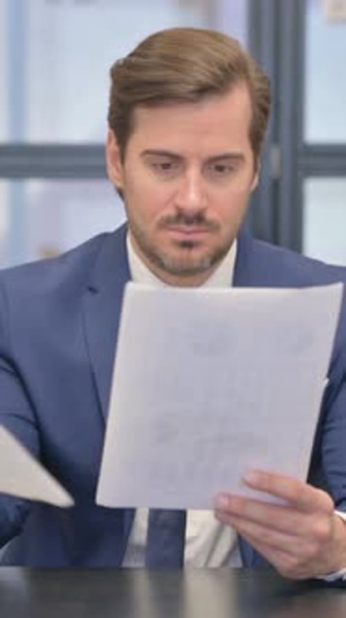 Young Businessman Reading Documents in Office, vertical video