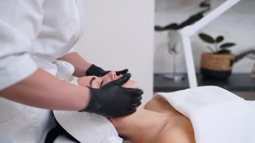 Professional Aesthetician Performs Antiaging Neck and Facial Massage on Client in Modern Spa Skilled