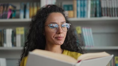 Une femme latino-arabe lit un livre, un manuel, un roman policier, une histoire policière, une bibliothèque de volumes, une fille intellectuelle