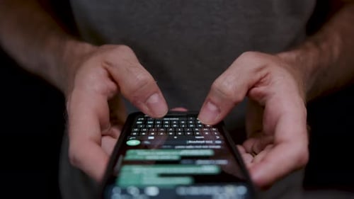 Young man holding a mobile phone close up, using it to write and send messages. Concept mobile techn