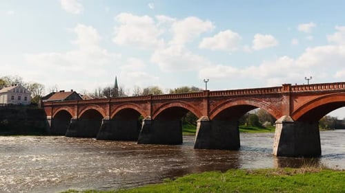 Arch Bridge Over Water on Sunny Day in Natural Landscape