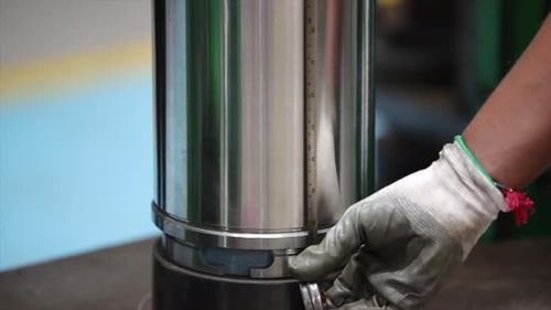 Le technicien utilise un ruban à mesurer flexible en acier pour vérifier la hauteur exacte d'un cylindre poli.