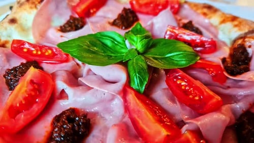 Close-up of fresh pizza with ham and tomato toppings