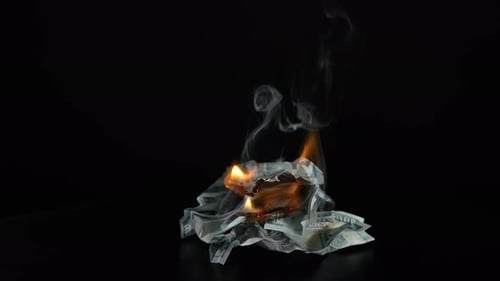 Brennende Dollarbanknoten auf schwarzem Tisch vor dunklem Hintergrund